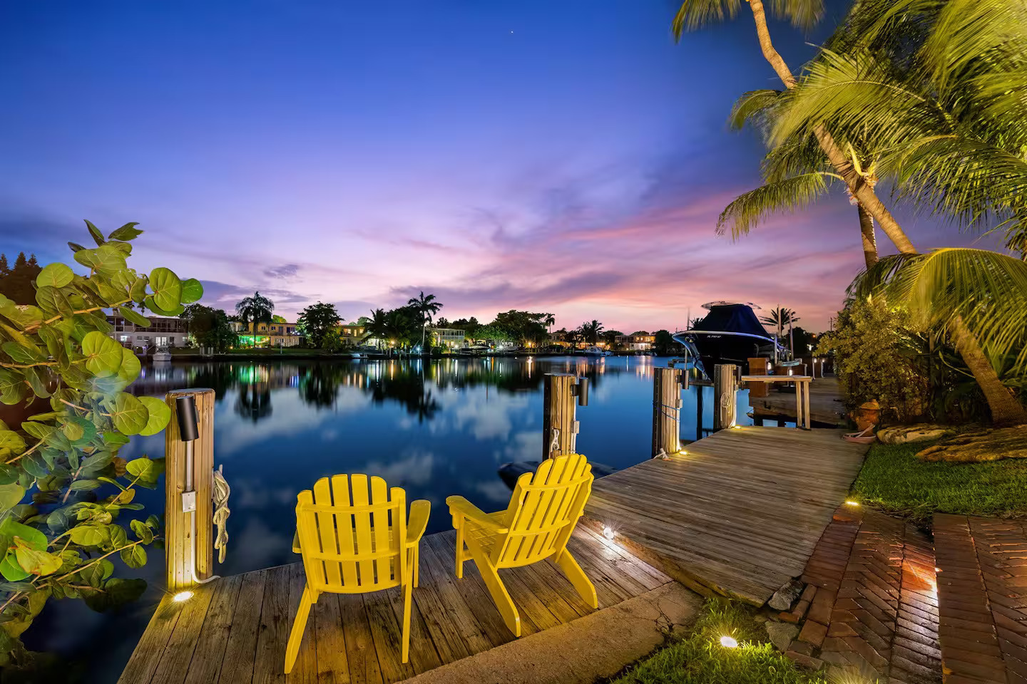 Private waterfront dock with yellow chairs, boat lift, and canal views — Pompano Beach luxury vacation rental